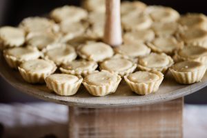 Mini banana pudding tartlets on a rustic wood stand—ideal for weddings, parties, or casual dessert tables.