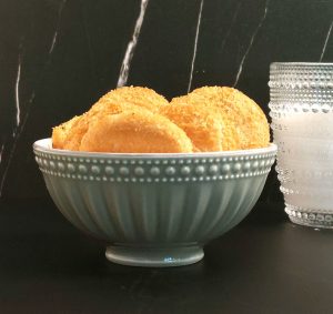 Golden brown French sablé cookies stacked in a decorative bowl with a textured glass of milk beside them, perfect for Central Florida dessert tables at weddings, corporate events, and upscale parties.