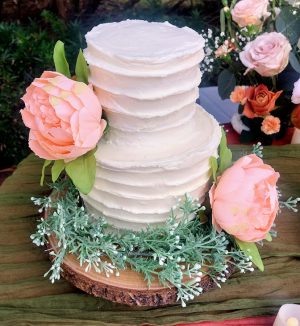 Two-tier white buttercream wedding cake with peach florals at Cypress Grove Estate in Orlando, Florida.