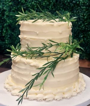 Two-tier buttercream sweetheart cake with textured icing and fresh greenery accents, designed for a wedding celebration at Trellis 925 in Orlando, Florida. A classic and elegant option from The Cookie Jar's custom wedding cake collection.