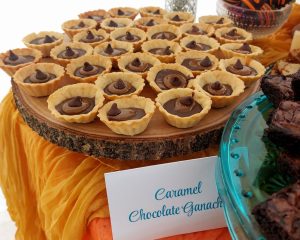 Mini tartlets filled with rich caramel chocolate ganache, elegantly arranged on a rustic wood slice for a wedding dessert table in Orlando.