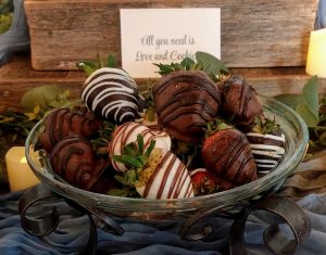 Glass dish filled with gourmet chocolate covered strawberries on a rustic dessert table at Ever After Farms, perfect for weddings in Orlando.