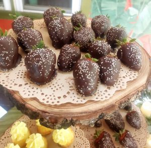 Chocolate covered strawberries with white nonpareils on a rustic wood slice stand at Riverpark Terrace in New Smyrna Beach. Ideal for weddings, corporate events, and garden-themed parties in Central Florida, Orlando, Daytona, and St. Augustine.