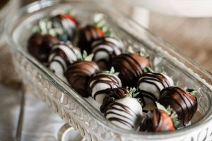 Elegant glass tray filled with chocolate covered strawberries, displayed on a rustic chic wedding dessert table at The Great Escape venue in Clermont, Florida.