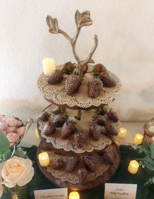 Elegant display of chocolate covered strawberries on a tiered wooden stand, featured at a wedding dessert table at Sterling Event Center. Perfect for weddings and parties in Central Florida, Orlando, Daytona, and St. Augustine with a romantic garden theme.