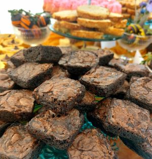 Stacks of rich chocolate fudge brownies with a glossy, crackled top, served on a teal glass stand as part of a wedding dessert table at Danville Bed & Breakfast in Geneva, Florida. A decadent treat by The Cookie Jar Orlando for weddings, parties, and events.