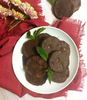 Plate of chocolate mint French sablé cookies garnished with fresh mint leaves, perfect for weddings, showers, or corporate dessert trays in St. Augustine.