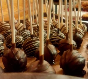 Rich chocolate truffle cake pops drizzled in white chocolate, styled on a rustic dessert table at a Hidden Barn wedding — perfect for favors, sweet sixteens, parties, and elegant celebrations.