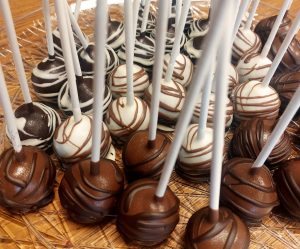 Assorted chocolate and white chocolate truffle cake pops with elegant drizzle designs, arranged on a clear dessert tray at a wedding reception at Trellis 925 in Orlando. A luxurious offering from The Cookie Jar Orlando, perfect for weddings, birthday parties, sweet sixteens, and corporate celebrations.