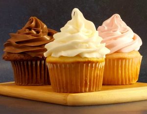 Three classic cupcakes in a row: chocolate cupcake with chocolate buttercream, vanilla cupcake with white buttercream, and strawberry cupcake with pink buttercream, perfect for parties, showers, and dessert bars.