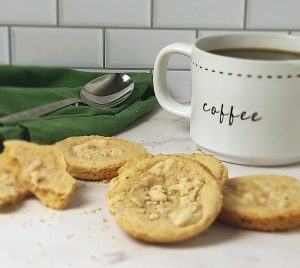 Soft and crumbly coffee cake cookies with streusel topping, styled beside a cozy mug of coffee and green napkin. A comforting choice from The Cookie Jar Orlando, ideal for elegant wedding dessert tables, corporate coffee breaks, party trays, and edible event favors.