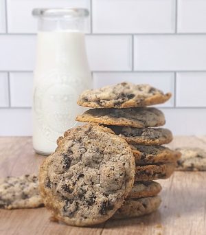 Stack of cookies and cream cookies filled with crushed chocolate sandwich cookies, with a bottle of milk in the background. A popular choice from The Cookie Jar Orlando for wedding dessert tables, celebration trays, and corporate events.