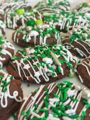 Rich dark cocoa cookies topped with white chocolate drizzle and green, silver, and white holiday sprinkles. Perfect for seasonal parties, corporate gatherings, dessert trays, and festive celebrations by The Cookie Jar Orlando.