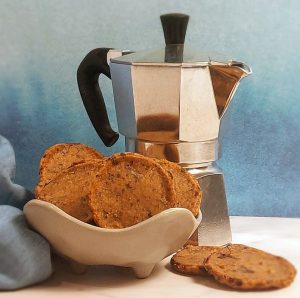 Elegant espresso chocolate chip French sablé cookies served in a ceramic dish beside a moka pot—perfect for wedding dessert tables and upscale events across Central Florida.