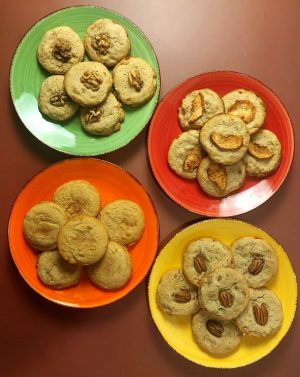 Four colorful plates with fall cookies: maple walnut, caramel apple, pumpkin spice, and butter pecan for seasonal dessert tables.
