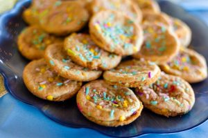 Funfetti birthday cake cookies topped with colorful sprinkles on a blue glass plate, perfect for weddings, parties, and corporate events in Central Florida.