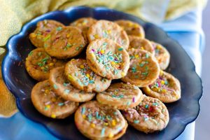Colorful funfetti birthday cookies with rainbow sprinkles displayed on a deep blue glass plate for weddings, corporate events, and parties in Central Florida.