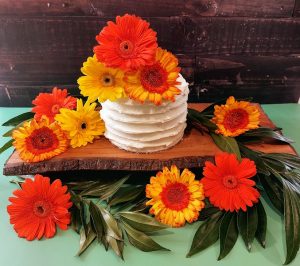 Small wedding cake with buttercream frosting and gerbera daisies, perfect for colorful weddings and events in Central Florida.