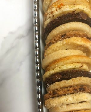 Close-up of a tray filled with an assortment of French sablé butter cookies in various flavors, ideal for upscale dessert tables at weddings and parties in St. Augustine.