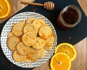 Delicate French butter cookies infused with honey and orange zest, artfully plated with fresh orange slices and honey—ideal for weddings, showers, and elegant dessert tables in St. Augustine.