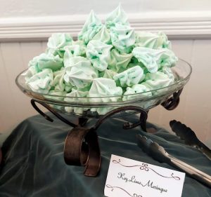 Glass bowl of green key lime French meringue cookies on display at a wedding dessert table at Venue 1902 in Sanford, near Orlando.