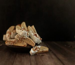 Handmade maple walnut biscotti cookies dipped in white chocolate and sprinkled with chopped nuts. A gourmet dessert option for weddings, parties, or corporate events in Central Florida, created by The Cookie Jar Orlando.