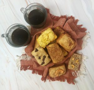 A cozy assortment of mini breakfast loaves, including chocolate chip, cinnamon, and nut varieties, served with coffee—ideal for morning weddings, brunches, corporate meetings, and breakfast parties across Central Florida, including Orlando, Daytona, and St. Augustine.