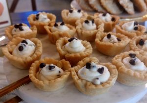 Mini tartlet shells filled with smooth cannoli cream and topped with chocolate chips, arranged on a marble platter for a wedding dessert table at Legacy Oaks in the Daytona area.