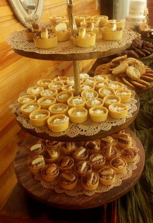Elegant three-tiered dessert stand filled with assorted mini tartlets: tiramisu, coconut cream, and banana cream. Displayed on a rustic wooden table at Club Lake wedding venue, perfect for Orlando-area receptions and special celebrations.