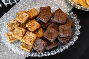 A crystal platter with bite-sized mocha brownies and caramel blondies, styled on a sparkling modern glamour dessert table at a wedding at New York Beer Project in Orlando, Florida. Elegant and decadent dessert bar display by The Cookie Jar Orlando.