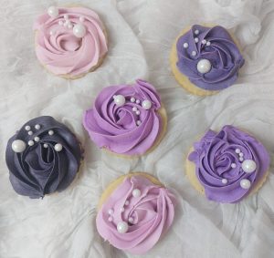 Elegant ombre cupcakes decorated with piped buttercream rosettes in shades of lavender, purple, and pink, topped with pearl sugar accents—ideal for weddings, bridal showers, baby showers, and Mother's Day.