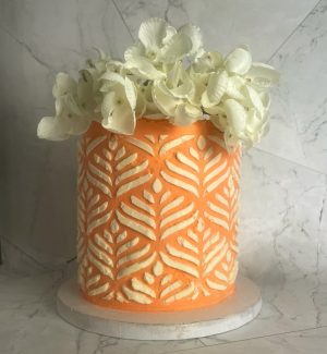 Tall peach buttercream wedding cake with bold piped pattern and white hydrangea topper in Central Florida.