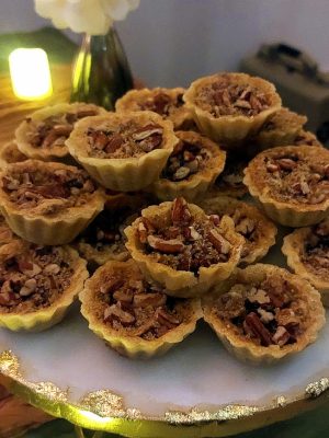 Bite-sized praline pecan tartlets arranged on an elegant gold-rimmed tray, perfect for rustic wedding dessert tables at Northwest Square in the Daytona area.