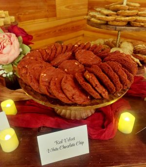 Platter of red velvet white chocolate chip cookies on display at rustic Orlando wedding dessert table with warm lighting.