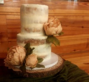 Semi-naked two-tier wedding cake with blush peonies at Club Lake Venue for rustic Orlando weddings.