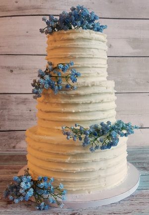 Four-tier textured buttercream wedding cake with blue baby’s breath florals for elegant Florida weddings and events.