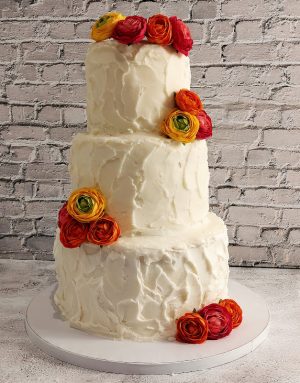 Rustic stucco buttercream wedding cake with bold ranunculus flowers for weddings in Orlando, Daytona, and St. Augustine.