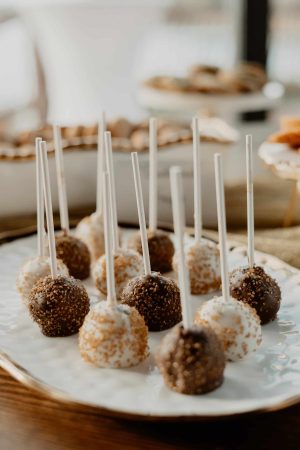 Elegant chocolate and white truffle cake pops topped with sparkling sugar crystals, arranged on a porcelain platter at a Casani Estates wedding dessert table in Orlando. These decadent treats by The Cookie Jar Orlando are perfect for weddings, sweet sixteens, birthday parties, and elegant celebrations. Each cake pop features a rich, fudgy center coated in smooth chocolate for a luxurious bite-sized favor.