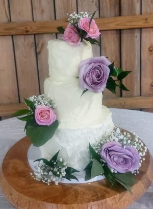 Three-tier white buttercream wedding cake with fresh lavender and pink roses for Pegasus Manor weddings in the Orlando area.